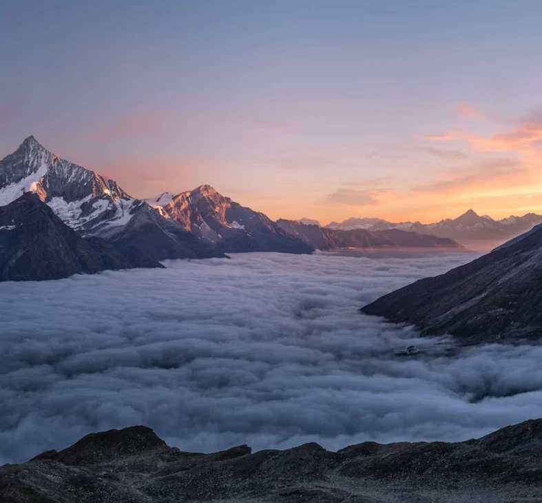 Sonnenaufgang über schneebedeckten Gipfeln die einen weiten Meer aus Wolken überblicken